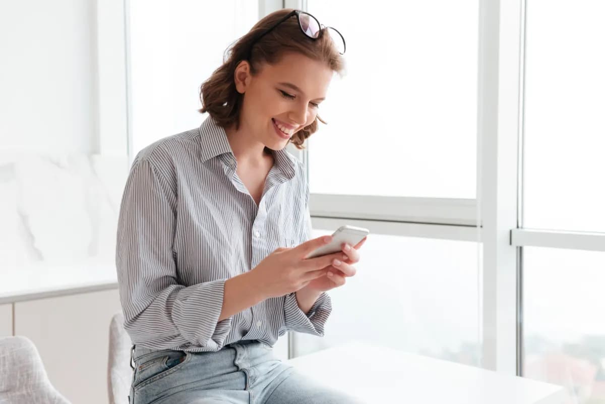 Woman smiling while reading a WhatsApp message on her phone