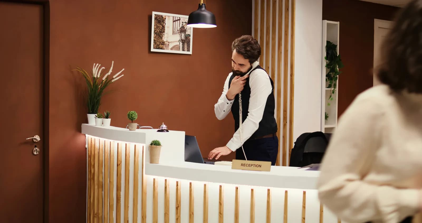 Recepcionista de un hotel boutique independiente atendiendo a un huésped en el mostrador